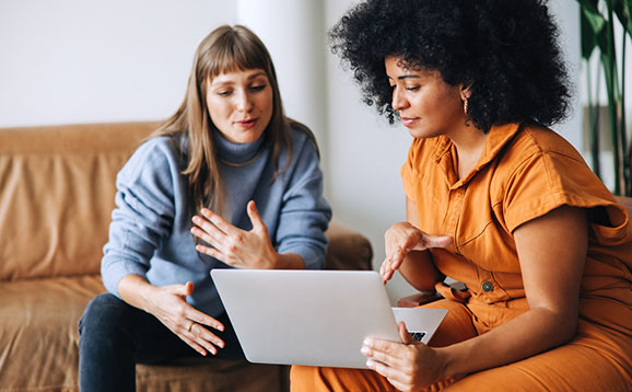 Two businesswomen having a discussion while looking at a laptop screen