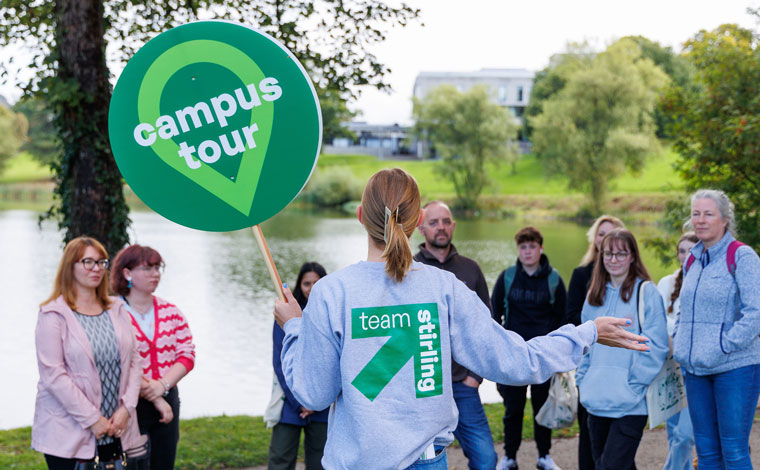 A confident student leading a campus tour