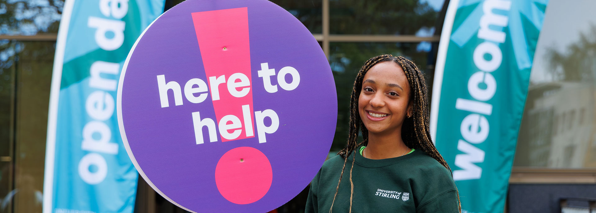 A helpful student with a lollipop sign that says 'here to help'