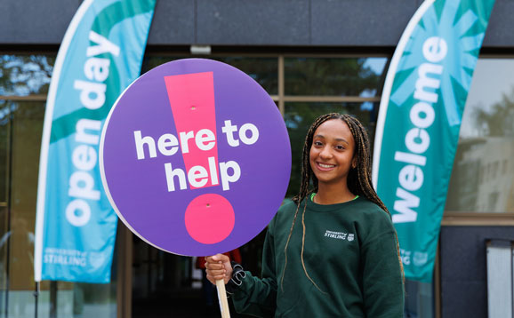 A student ambassador holding a sign that says 