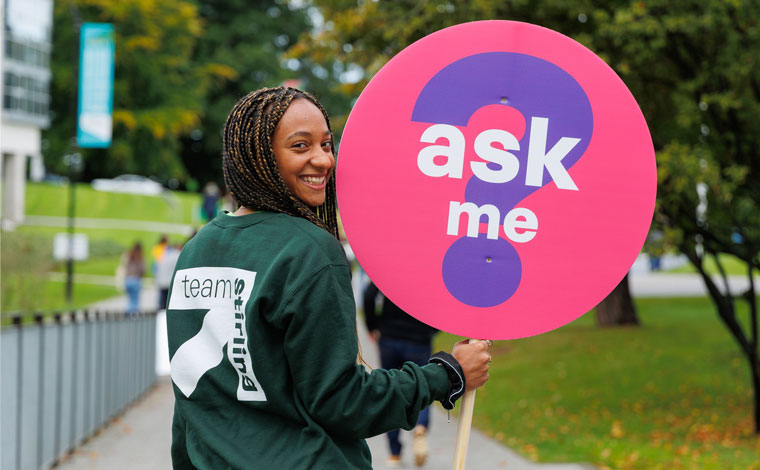 A helpful student holding a lollipop sign which says 