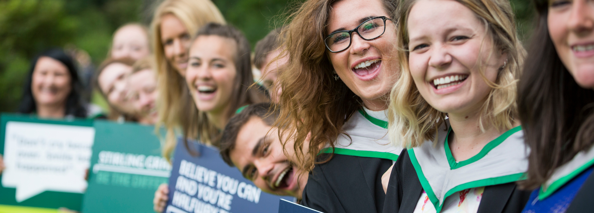 Students at graduation holding signs