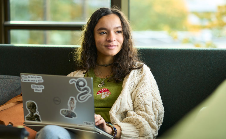 A thoughtful student sitting with their laptop