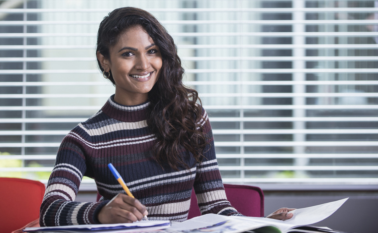 An enthusiastic student writing in a notebook