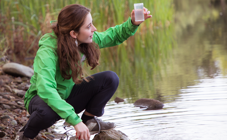 student taking water sample at river