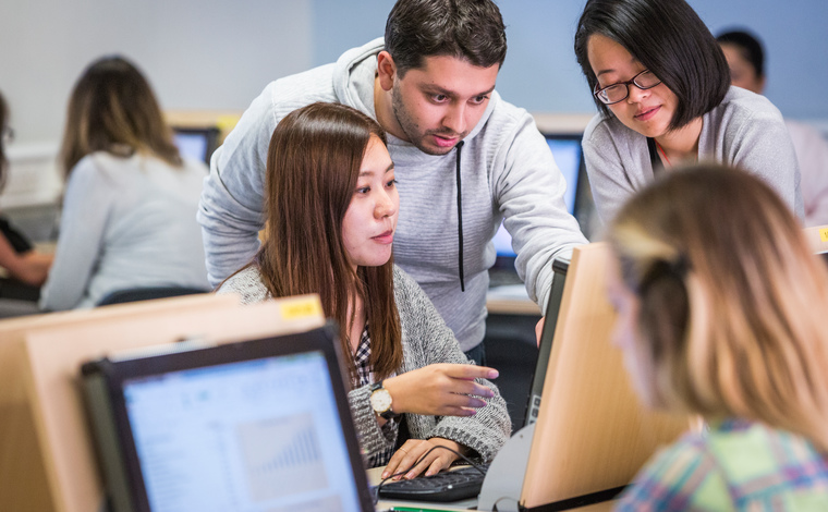 Group of students studying and talking in computer lab