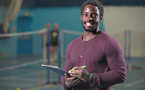 Student with a clipboard in the sports hall