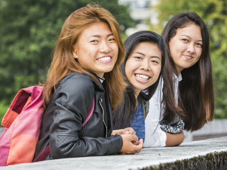 three students standing together on the loch bridge and smiling