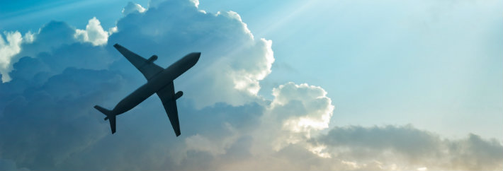 aeroplane flying across a cloudy blue sky 