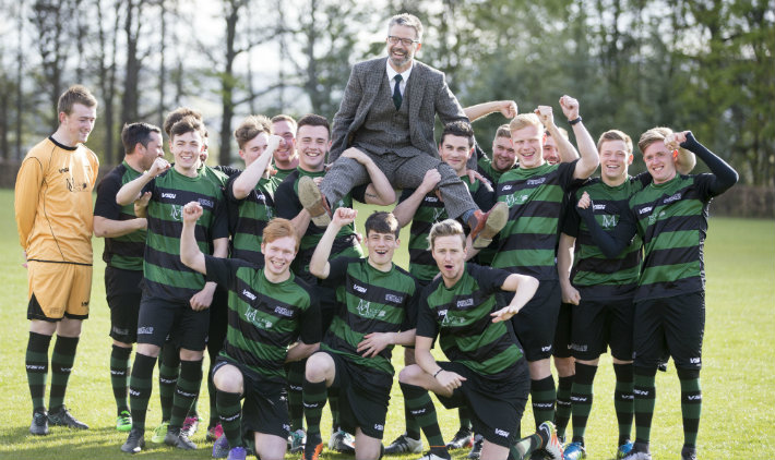 group of male football players holding up their coach on their shoulders