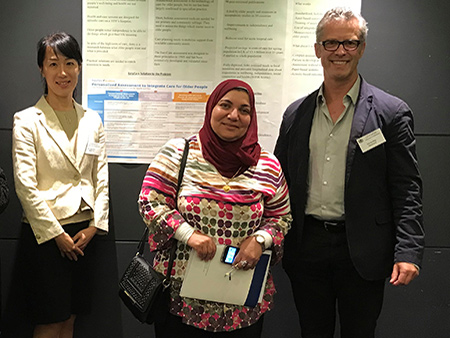 Ian Philp and two female colleagues standing in front of poster