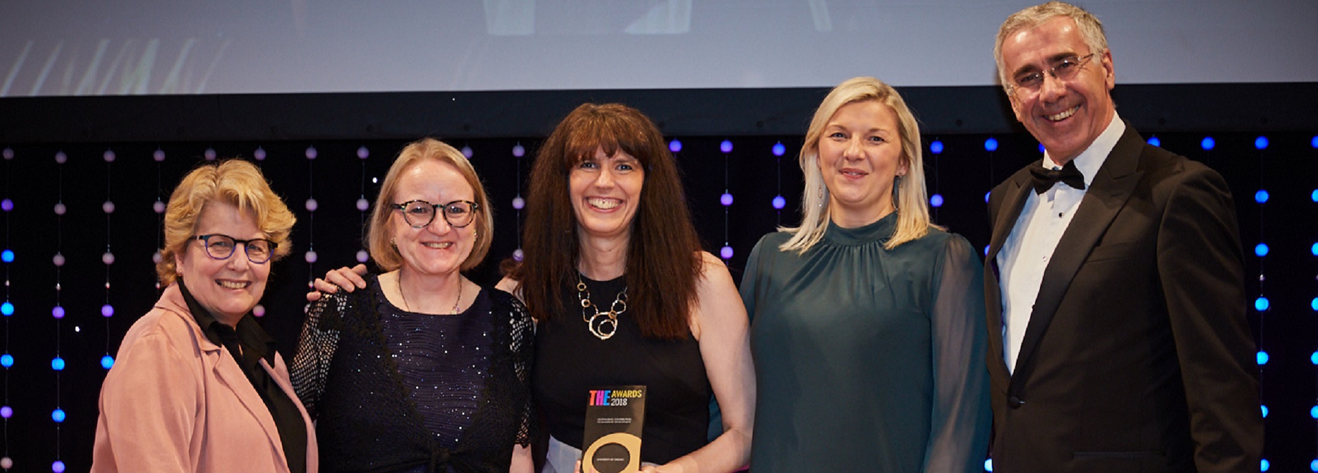 row of women and a man with an award