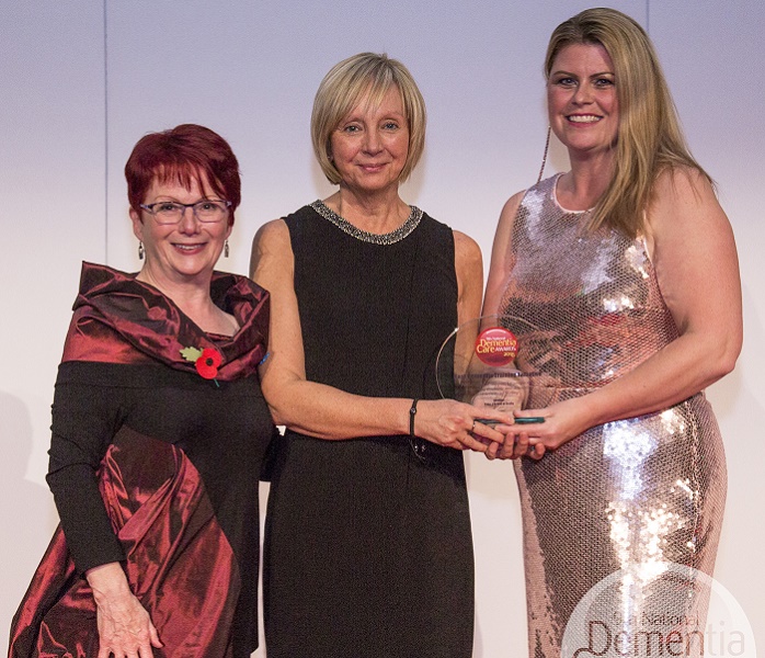 Three women in evening dress with award