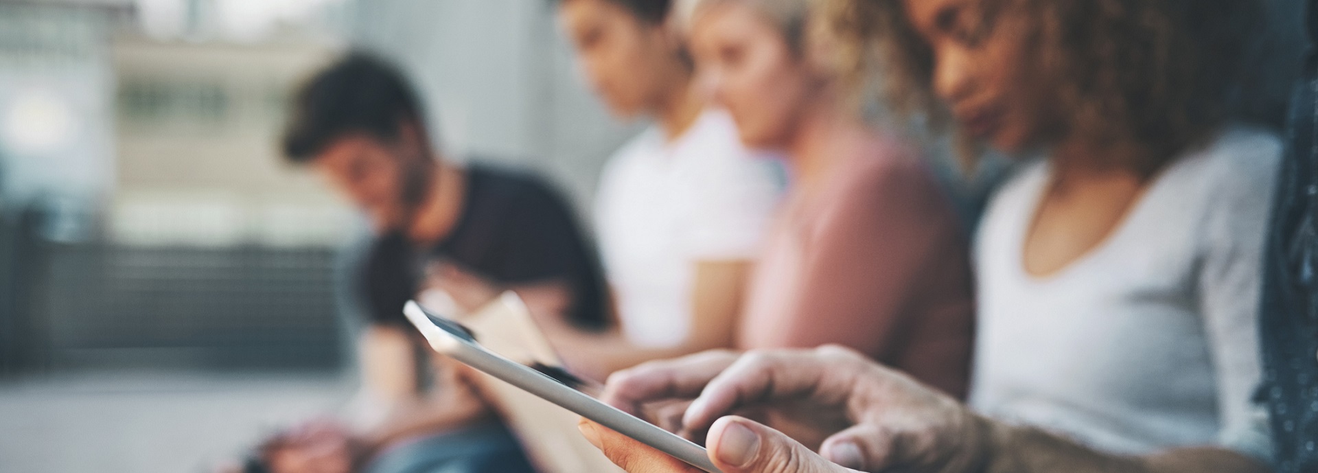 young people sitting in a row looking at mobile phones