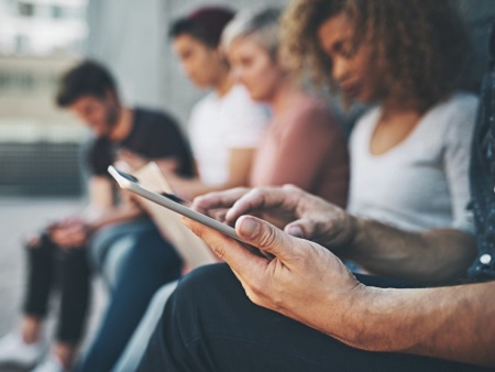 young people sitting in a row looking at mobile phones