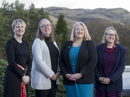 Four women in a row with hills behind