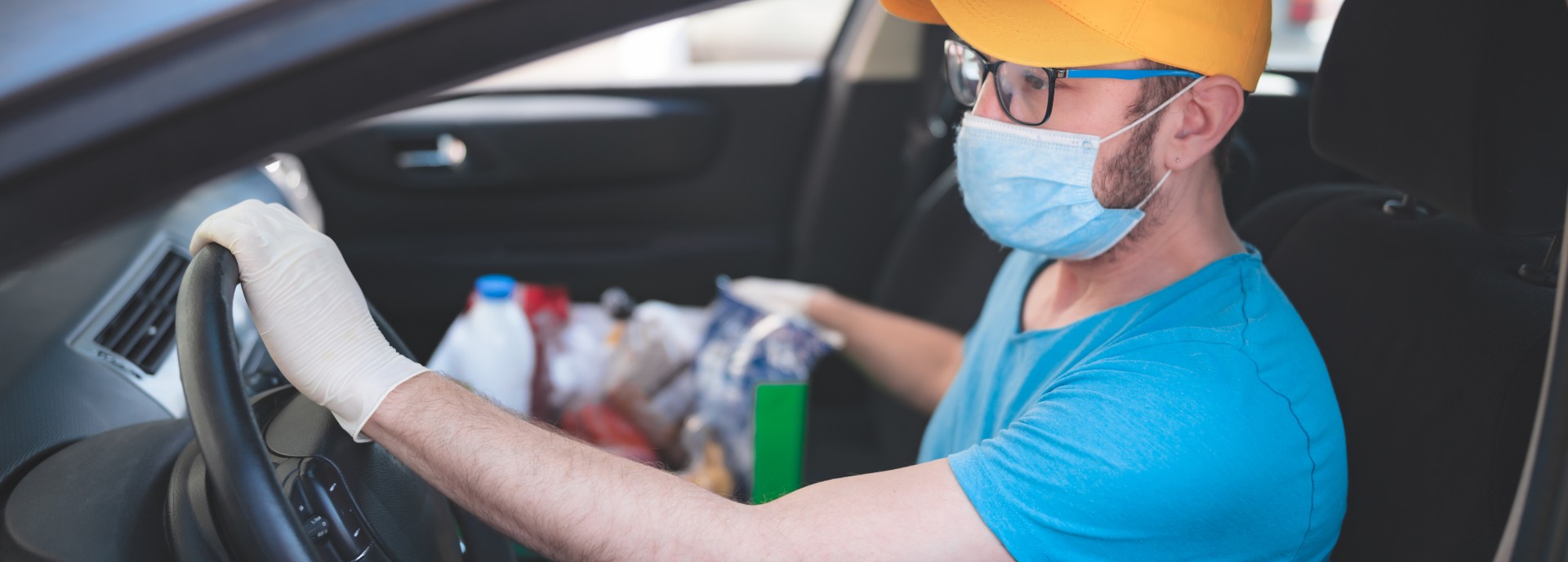 Delivery guy with protective mask and gloves delivering groceries during lockdown and pandemic.