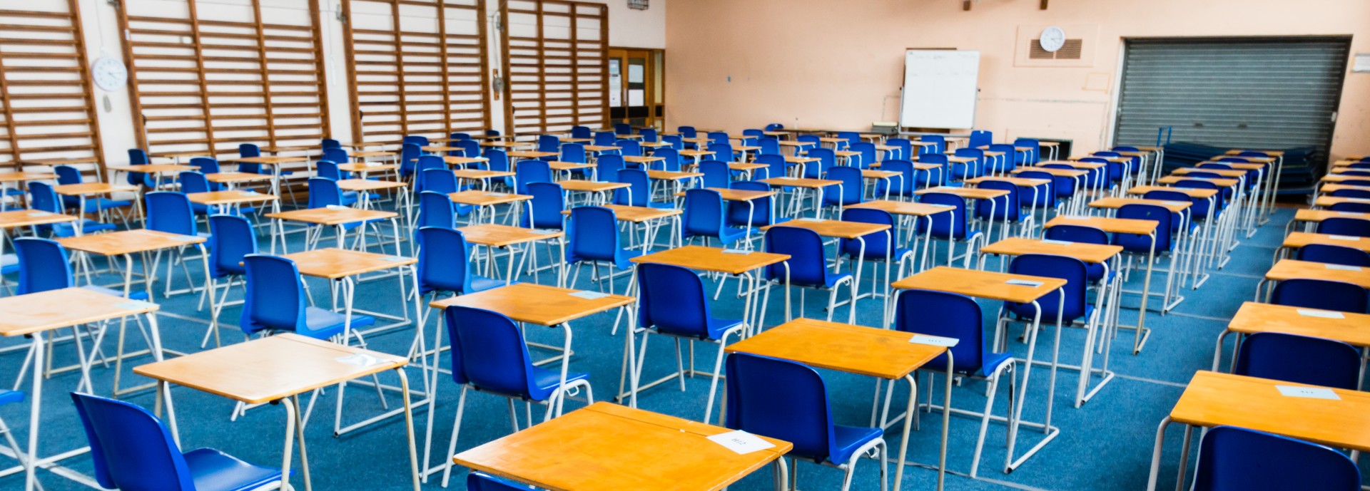 A school hall laid out with blue chairs and single desks