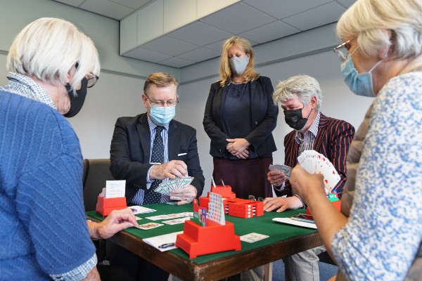 MSP Alexander Stewart joins players from the University's Bridge Club at a card table as they talk him through the game