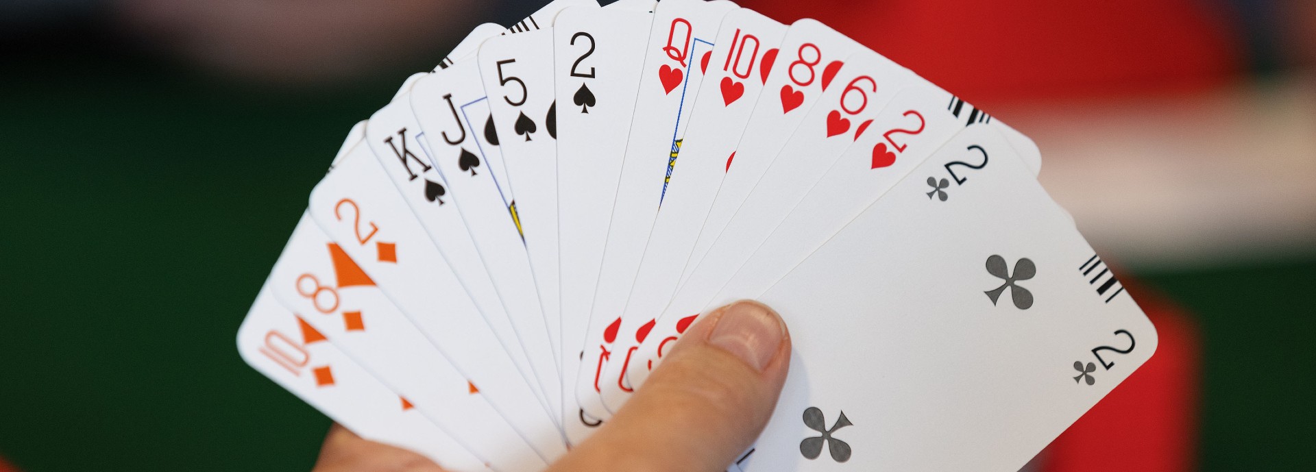 Hand holds up a deck of cards in a fan shape to camera