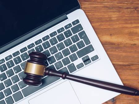 Judge gavel lying on top of laptop keyboard