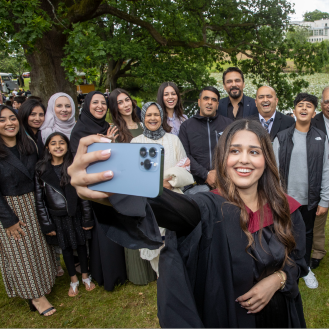 Girl takes selfie with large family group behind