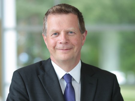 Professor Richard Oram wears a dark suit jacket, white shirt and blue tie.