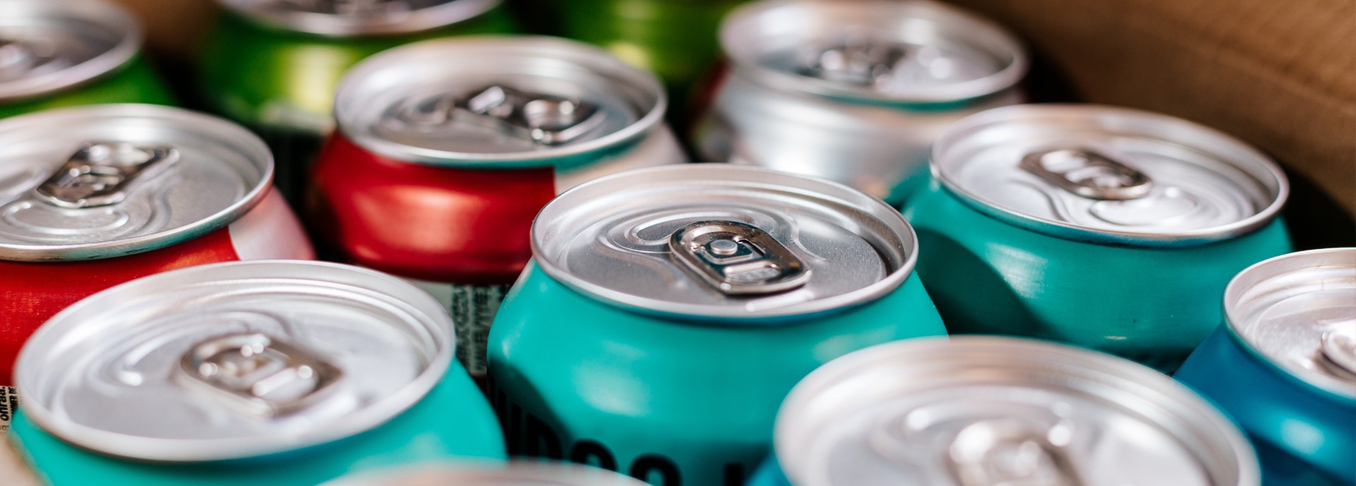 Close up image depicting an arrangement of metal beer cans in a row