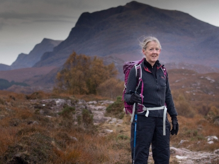 Helen Davies in hiking gear posing against a mountainous backdrop