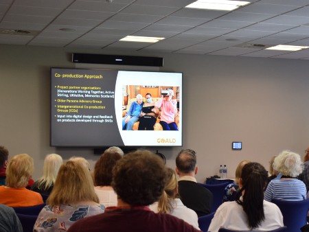 People seated in a conference room watching a presentation