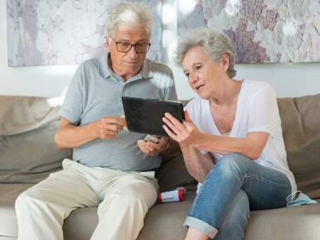 older people with tablet on sofa