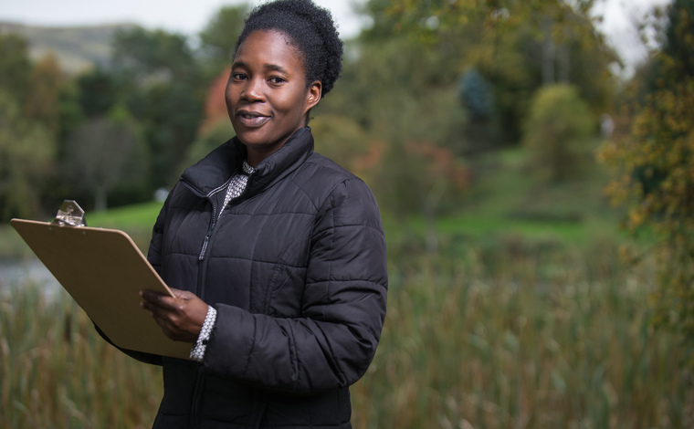 Female environmental sciences student with clipboard by loch