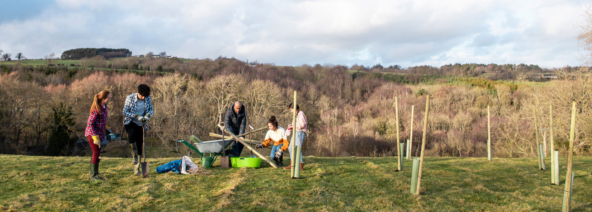 Family planting trees on hill