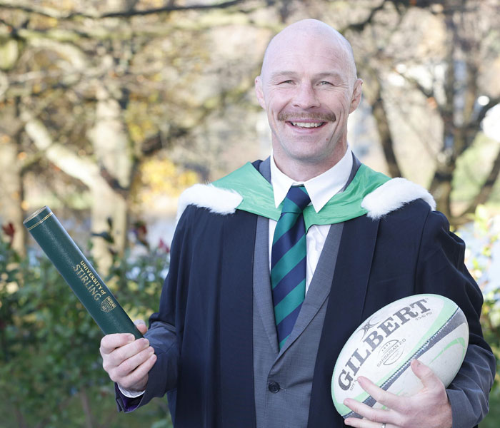 Steven McGinnis holding a rugby ball and scroll